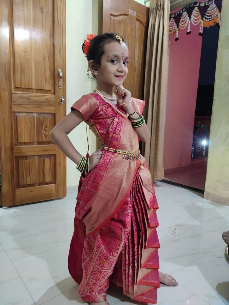 little girl posing in nauvari saree at home